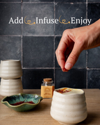 Hand reaching for a small jar on a wooden surface with text 'Add, Infuse, Enjoy' above.