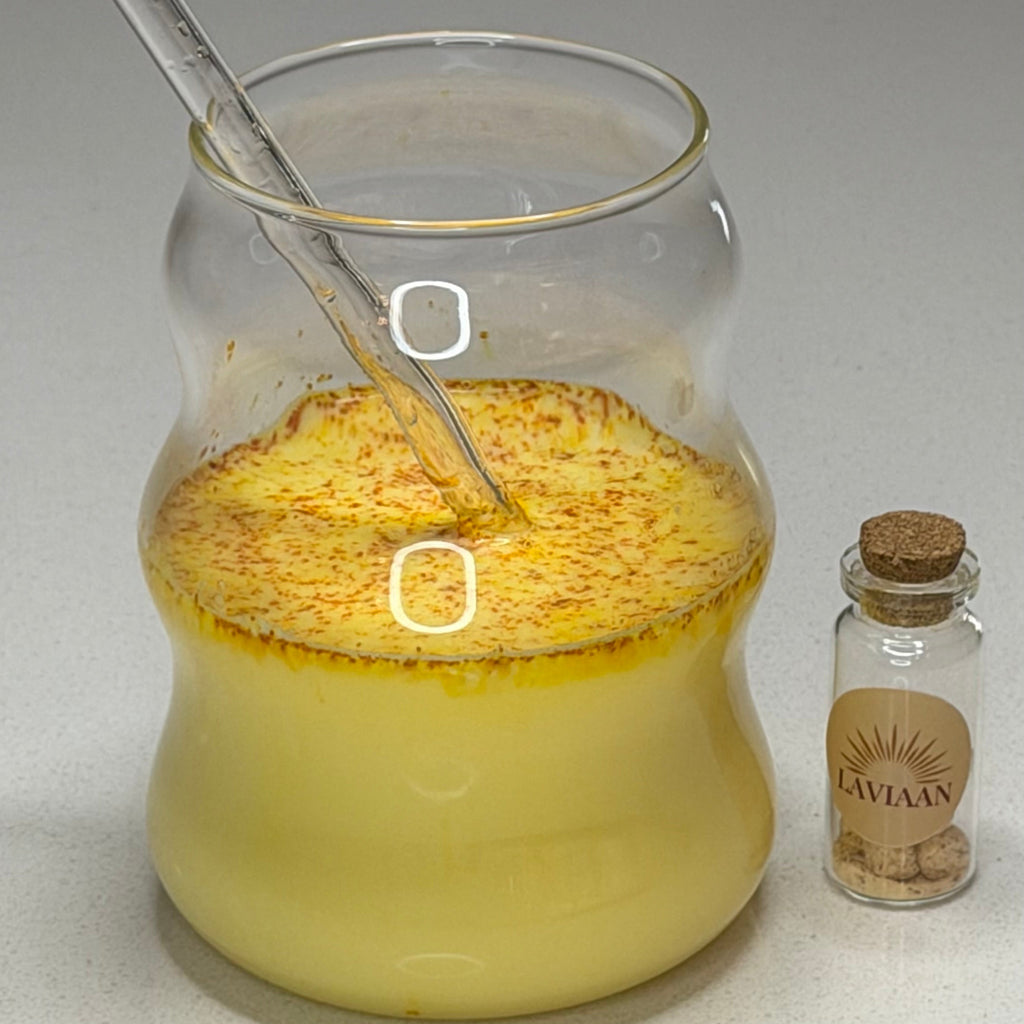 Glass jar with yellow powder and liquid, corked bottle labeled 'Bakvar' on a white surface.