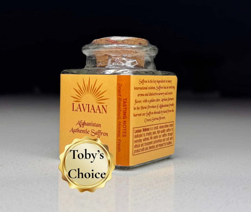 Small glass jar of Laviaan Afghan Saffron on a gray surface with a dark background