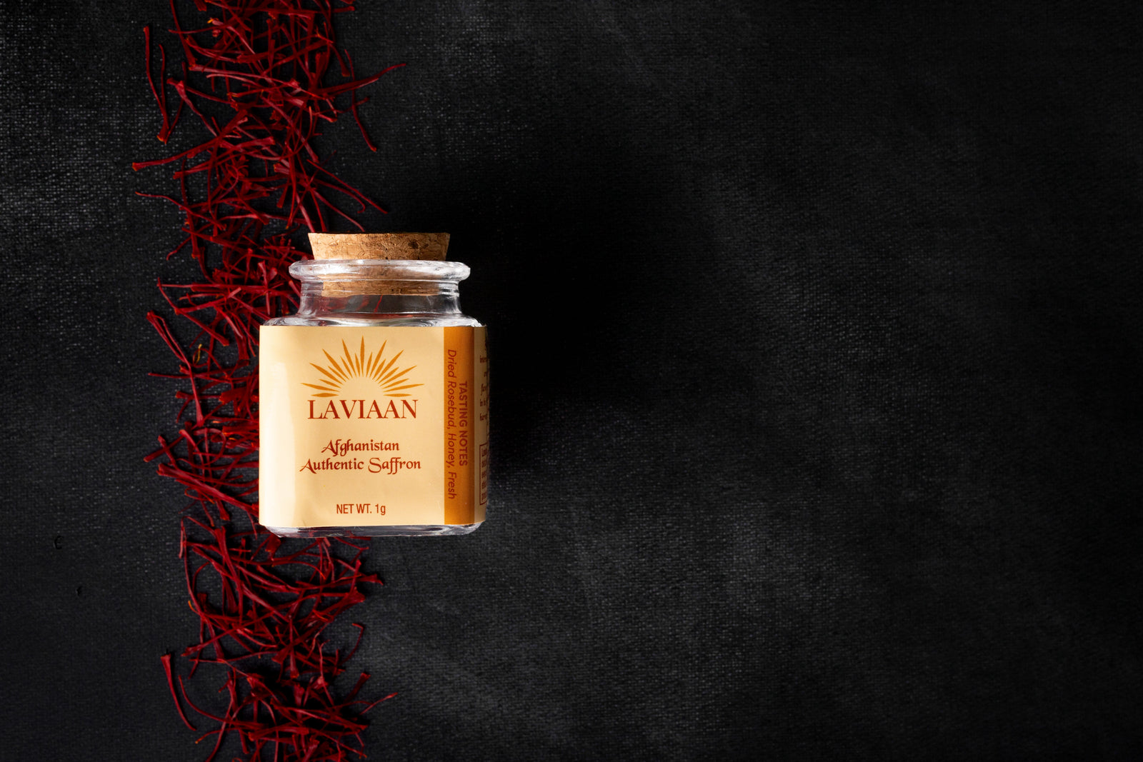 Jar of Lavinaan saffron on a dark background with saffron strands.